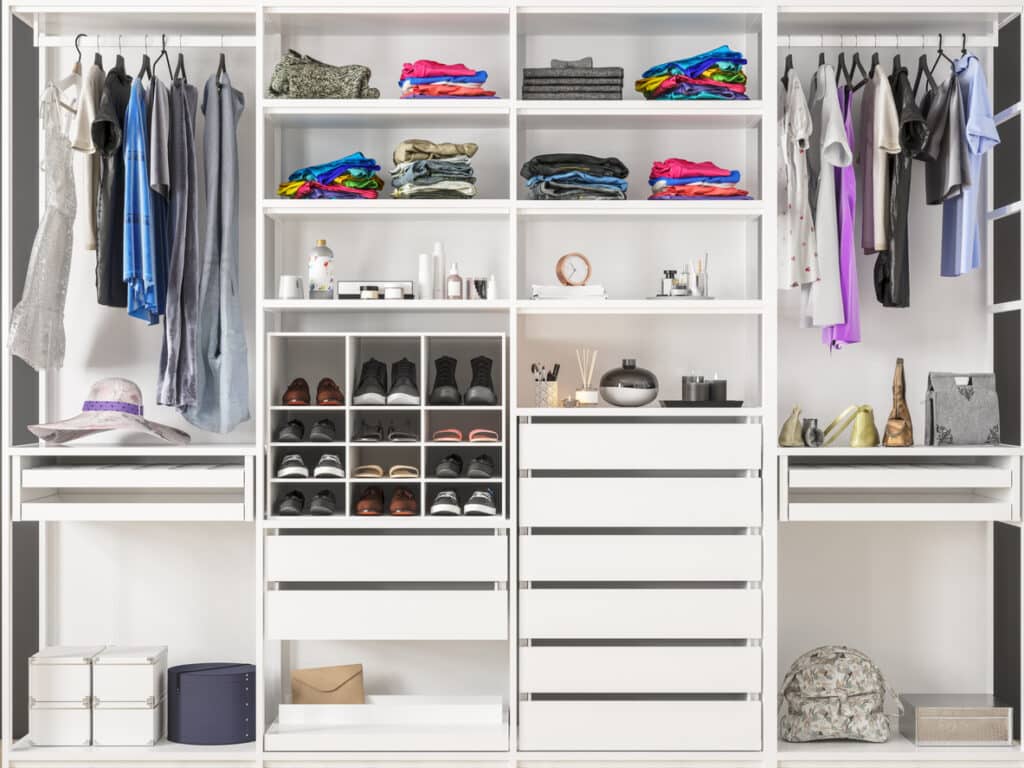 Fitted wardrobe interior showing full-height vertical storage — hanging rails, shoe cubbies, open shelving and drawers maximising small bedroom storage space