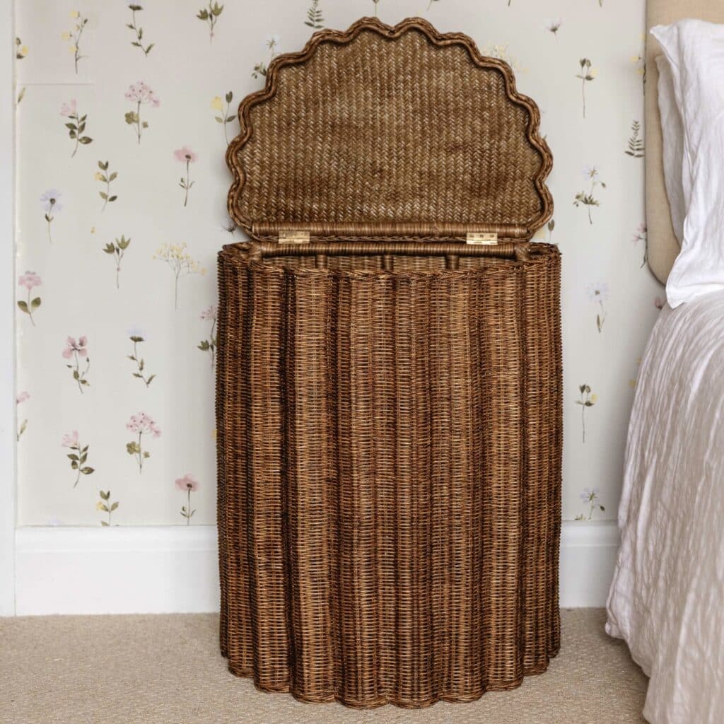 Shell Rattan Bedside Table and Storage Basket by HastshilpEngland — scalloped wicker bedside storage with hinged lid against floral wallpaper