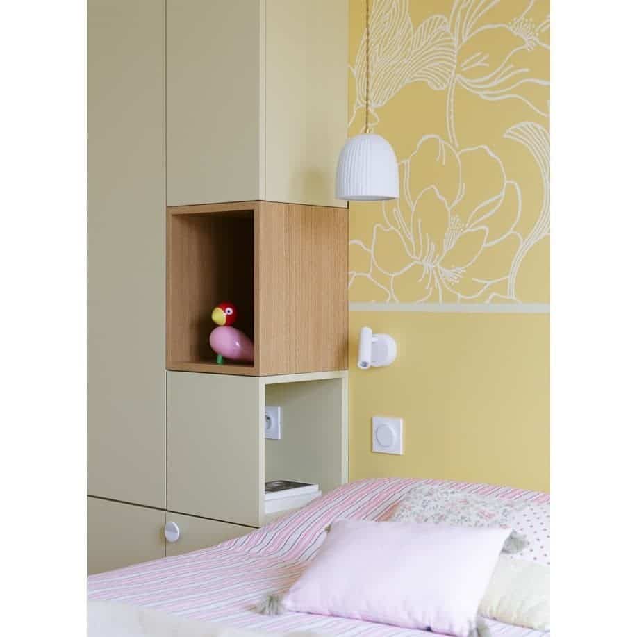 Built-in wardrobe with open niche shelf used as a bedside table in a children's bedroom — Farrow & Ball Yellow Ground paint and Helleborus wallpaper