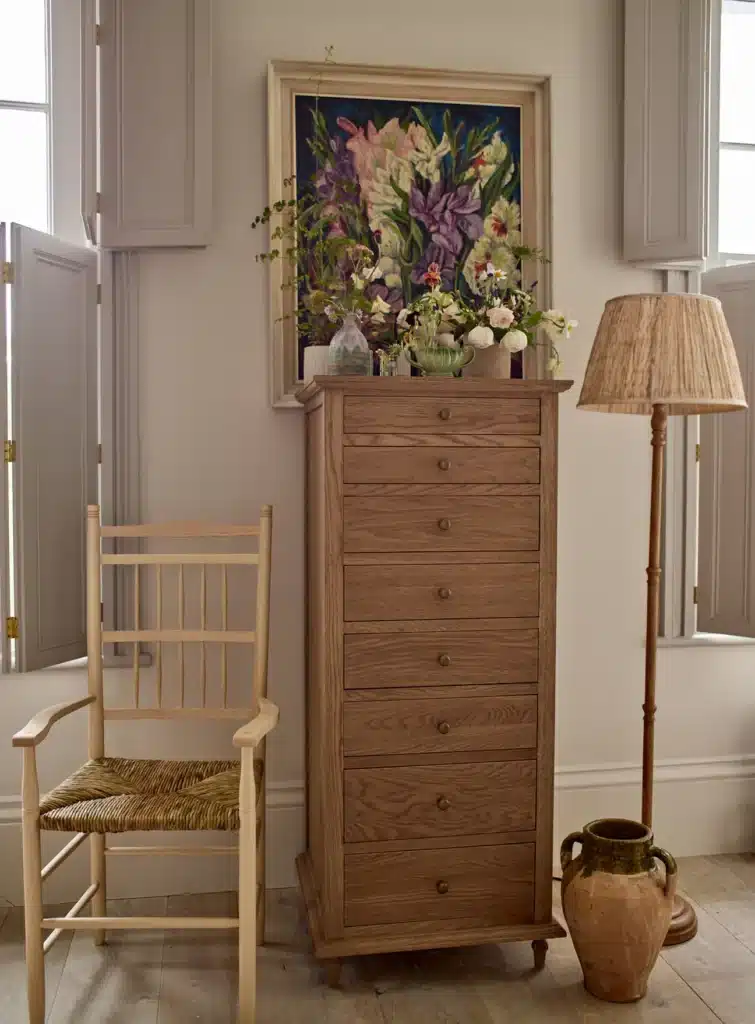 Rowen & Wren Latham Tall Chest of Drawers in solid oak — eight-drawer tallboy for small bedroom vertical storage, styled with floral artwork and rush-seat chair