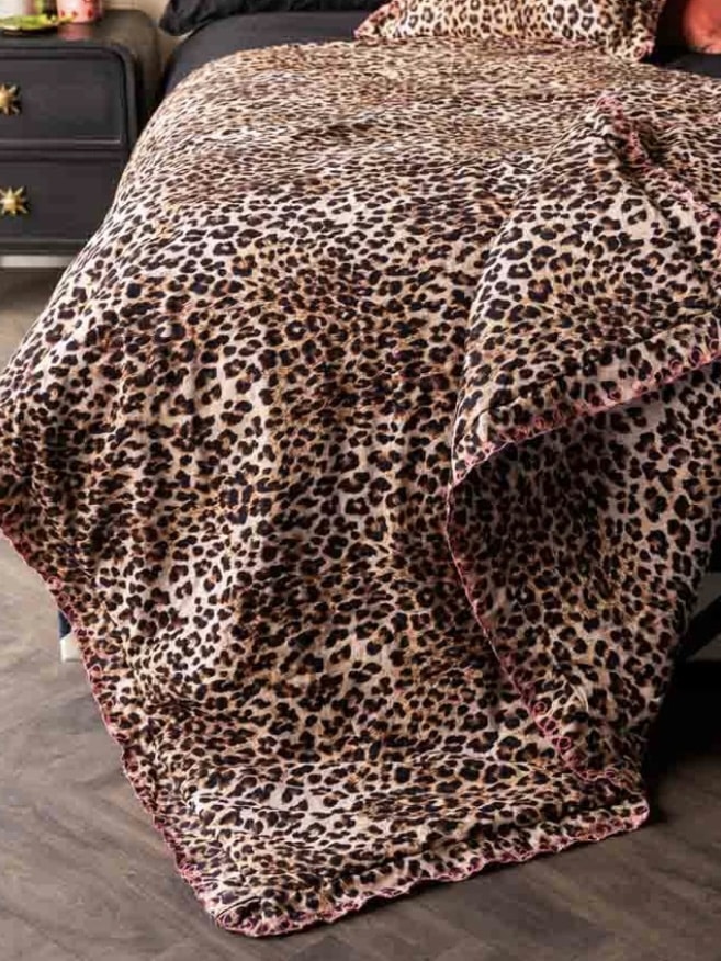 Leopard print scalloped edge quilt on a black bed with pink trim