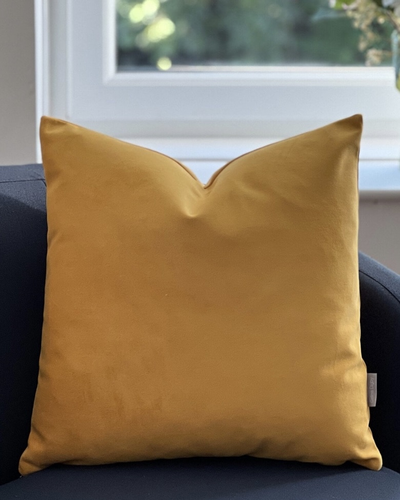 Mustard yellow velvet cushion on navy chair