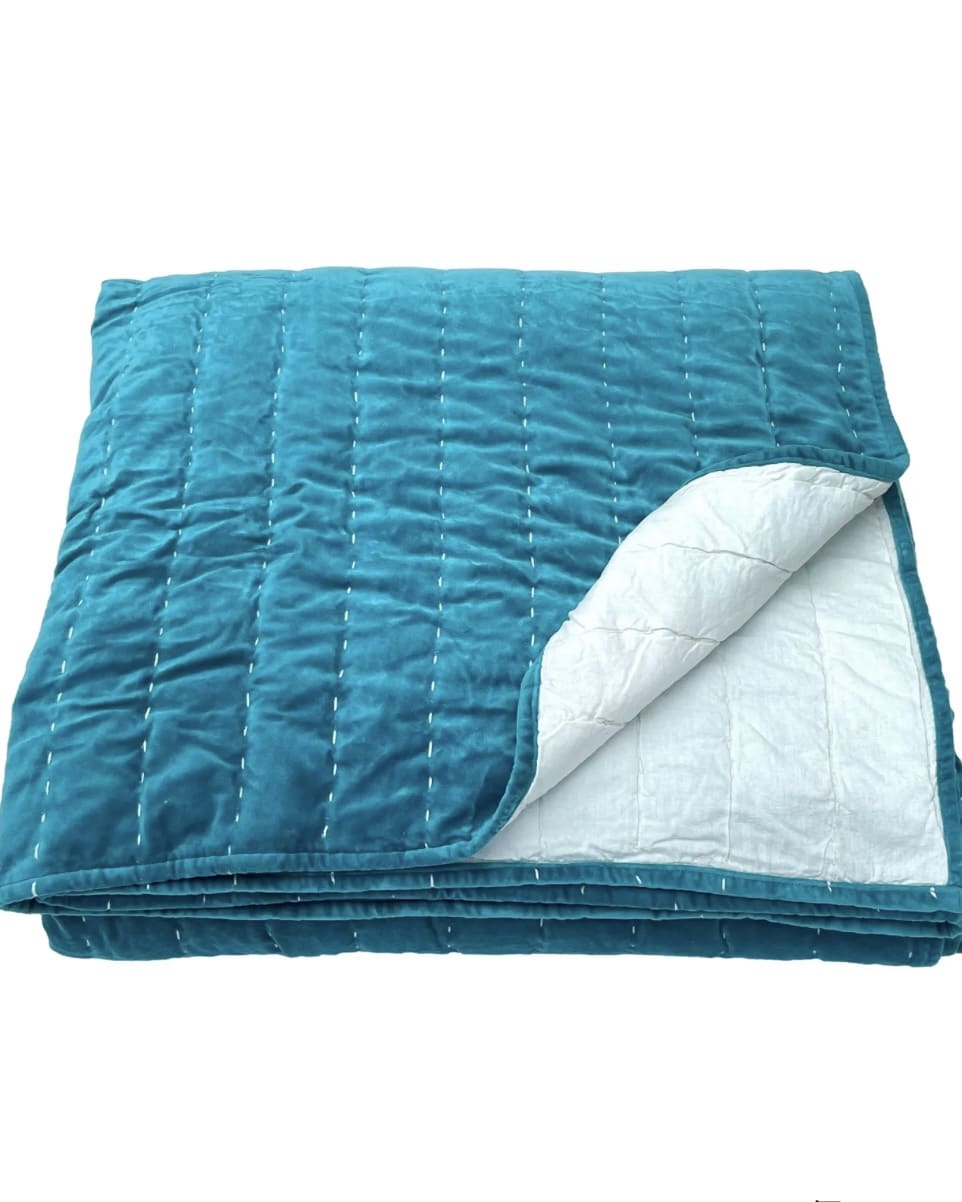 Peacock-blue quilted velvet bedspread with pale reverse side