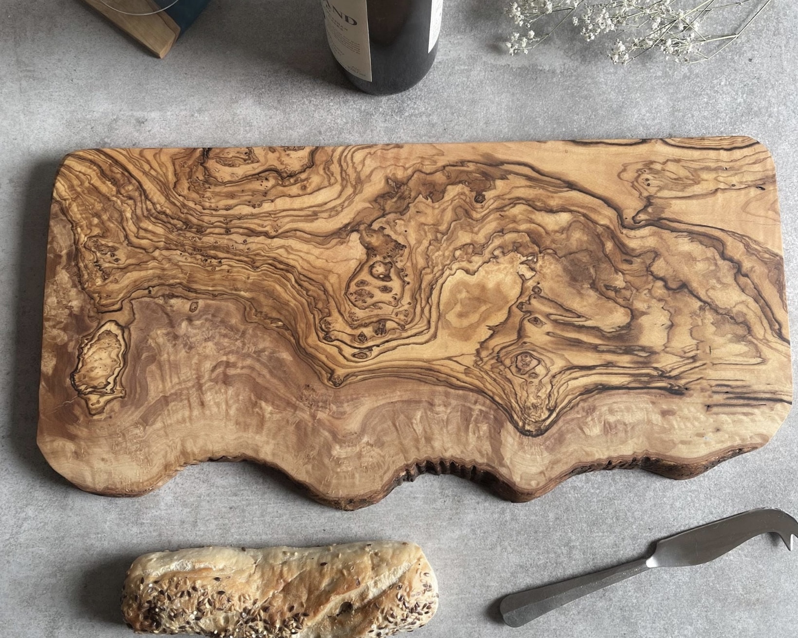 Organic olive wood charcuterie board with rich swirling grain pattern