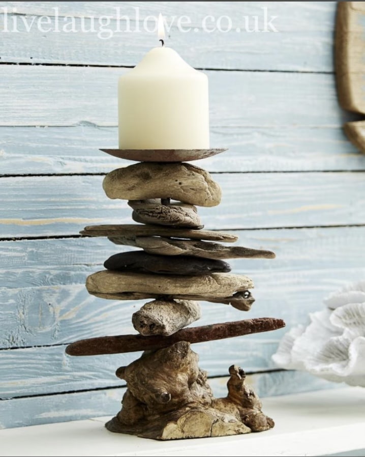 Rustic driftwood candlesticks styled against pale blue boards for relaxed coastal decor