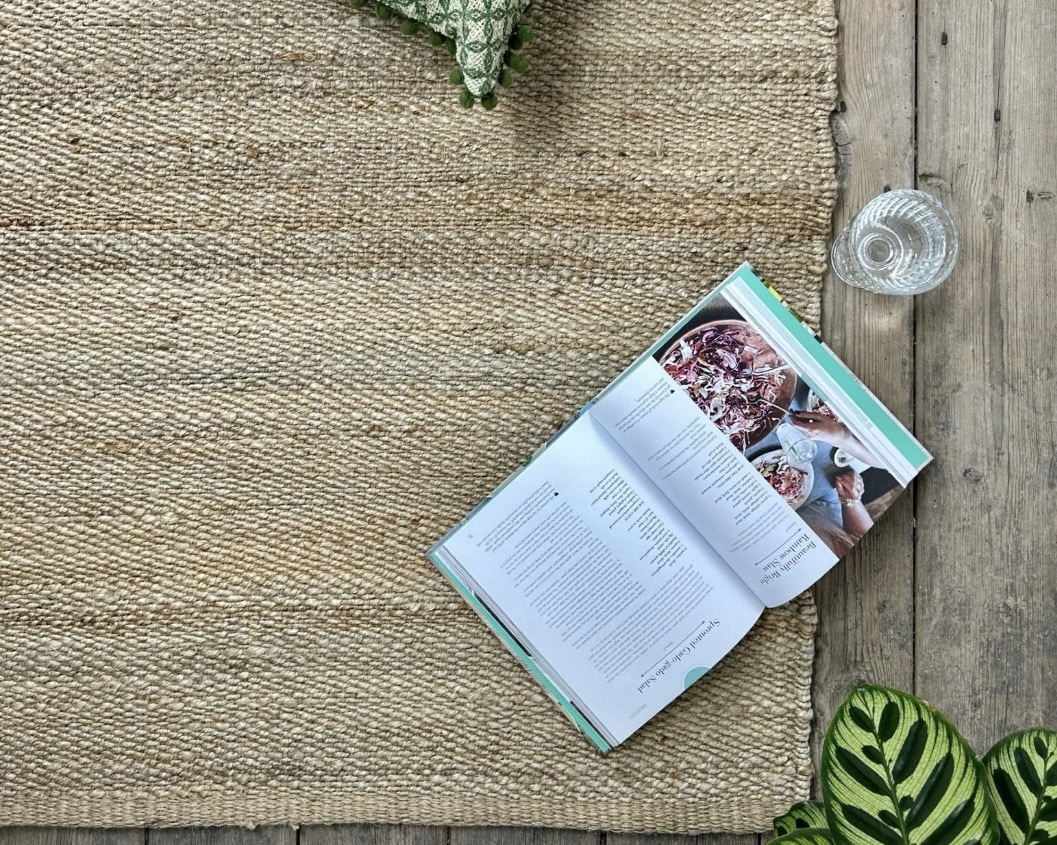 Natural jute rug on rustic floor adding sandy texture to a neutral coastal interior