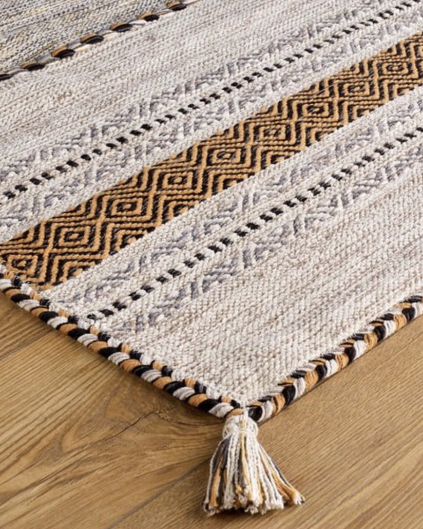 Beige kilim rug with black geometric stripe and tassel detail
