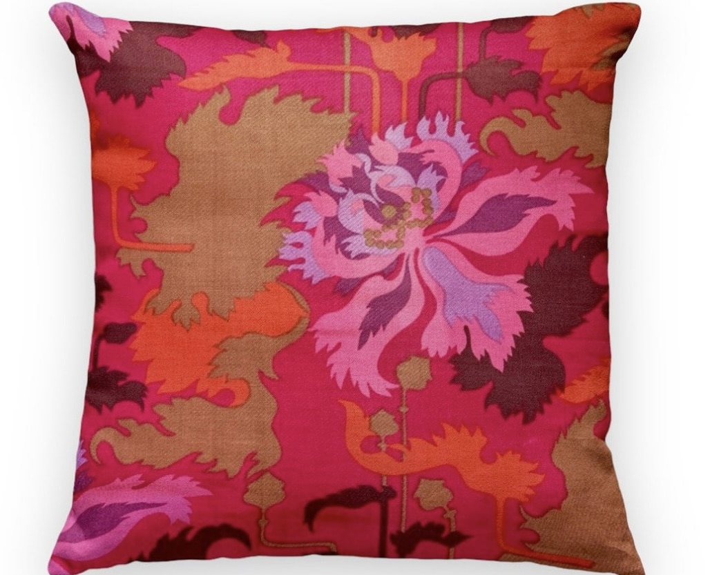 Hot pink and burnt orange floral cushion on a sofa
