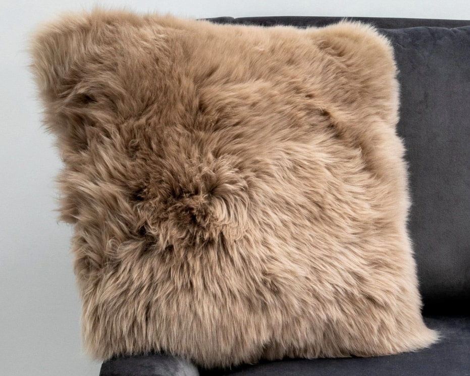 Caramel sheepskin cushion on a dark grey sofa