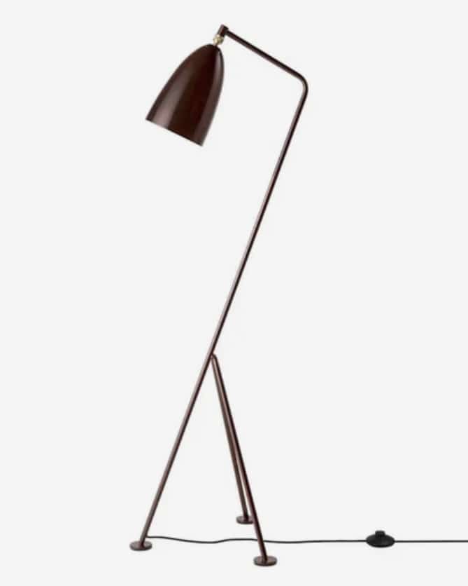 Walnut brown floor lamp with a sculptural silhouette adds drama in tan leather sofa living room