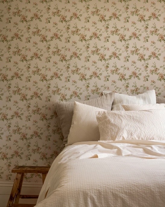 Cream Blush Field Rose Wallpaper by Piglet in Bed as a bedroom feature wall behind the bed, with soft blush roses on a warm cream ground — romantic bedroom wallpaper ideas for a cottage-style space.