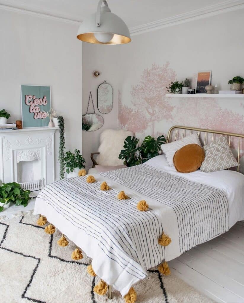 Pink bedroom mural wallpaper idea with Hua Trees Mural Wallpaper Pink by SianZeng behind a brass bed, styled with plants and mustard colour accents.