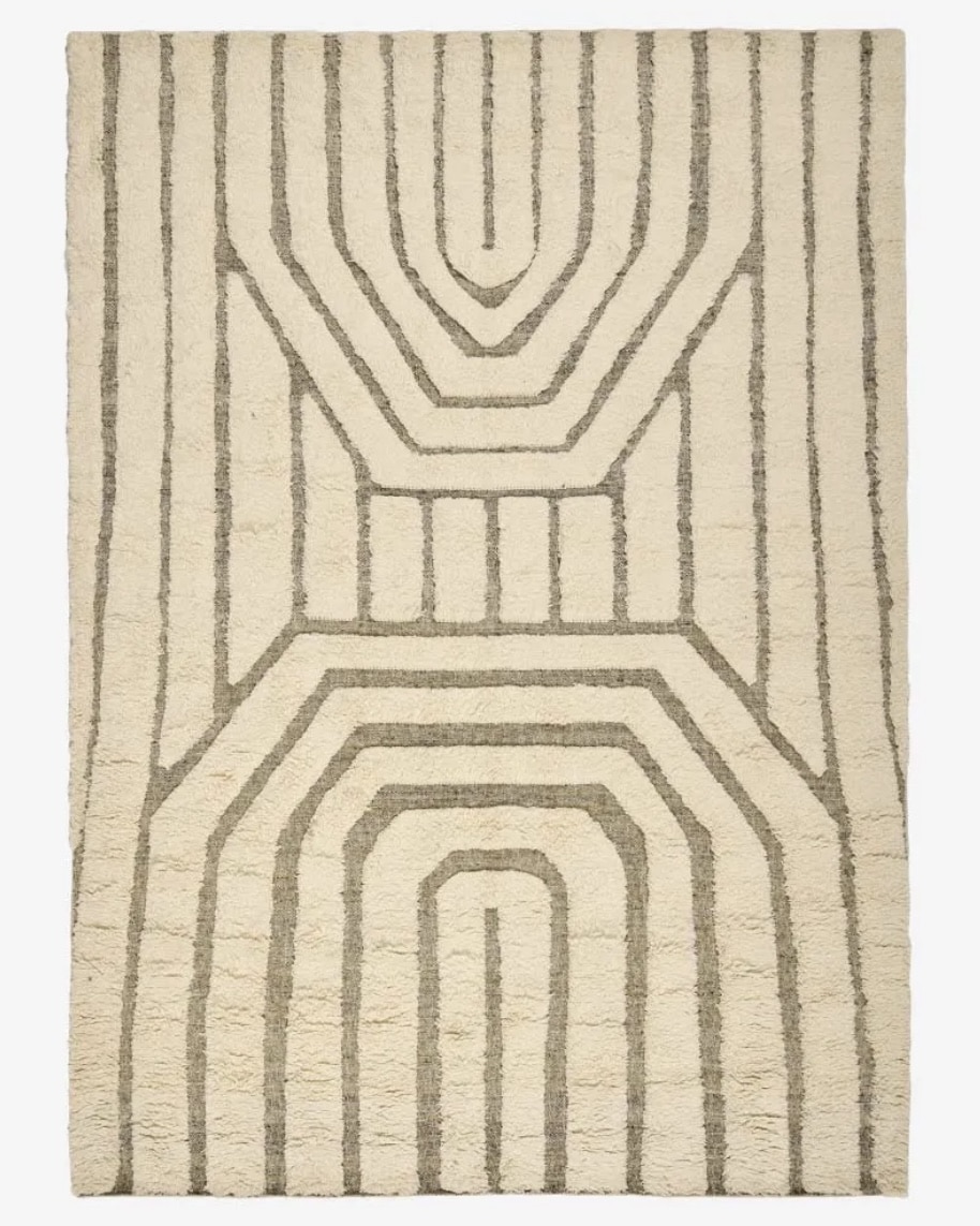 Close-up of a beige and taupe textured rug showing raised shaggy pile and woven base