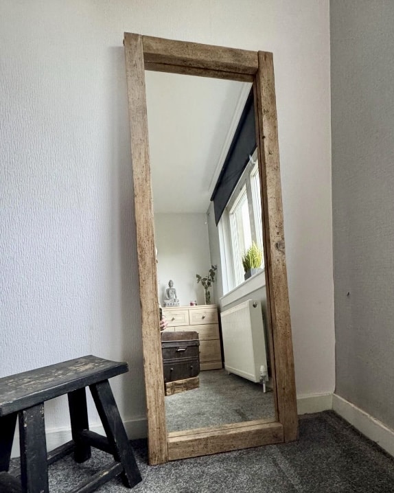 Chic boho bedroom styling: rustic wooden full-length mirror leaning against a wall.