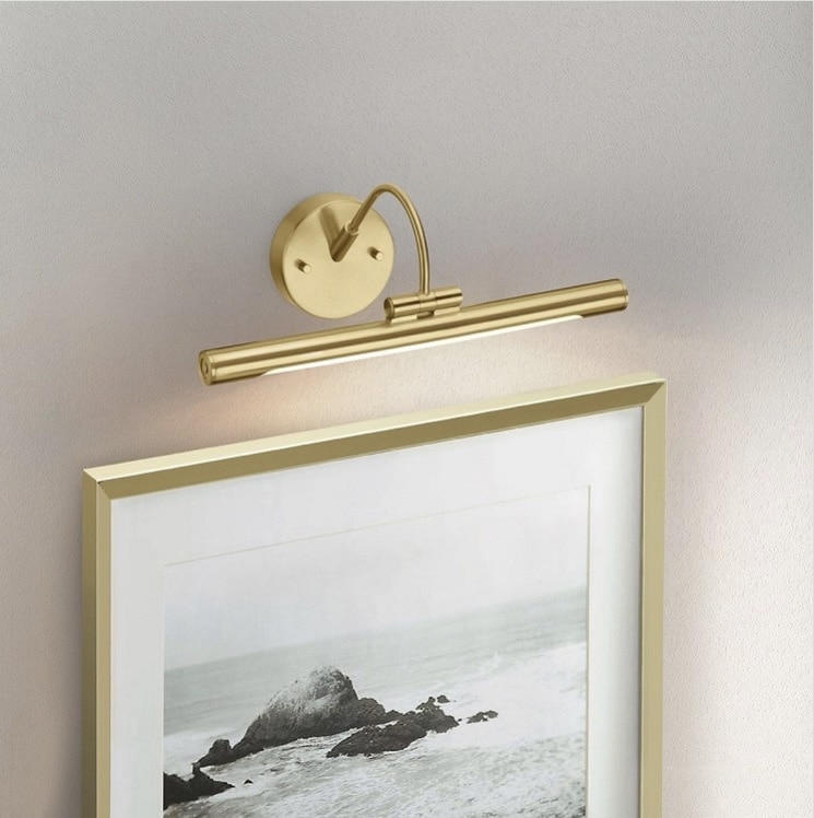 Brushed brass LED picture light above framed artwork, adding accent lighting to a living room wall.
