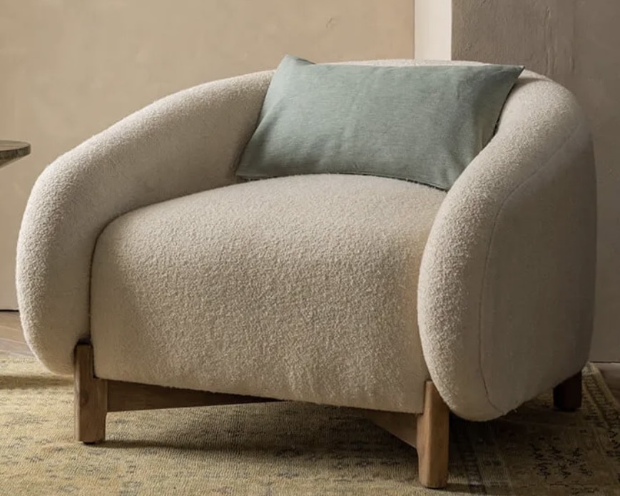 Off-white bouclé cocoon armchair with wooden feet for a cosy modern reading corner