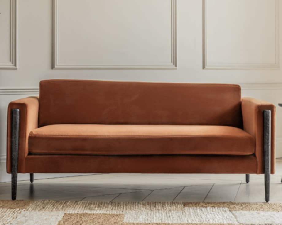 Rust velvet sofa with slim dark legs for an orange and blue living room scheme