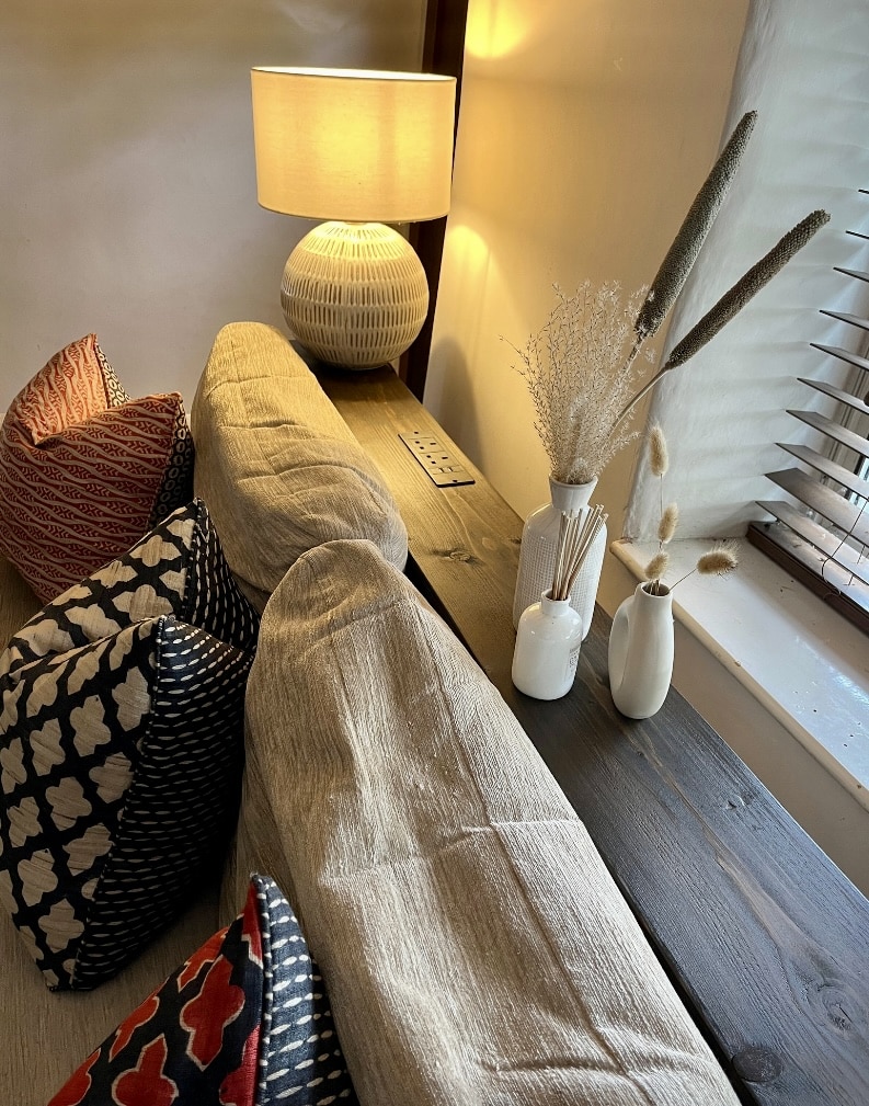 Slim console table placed behind a sofa with a table lamp and styling accessories