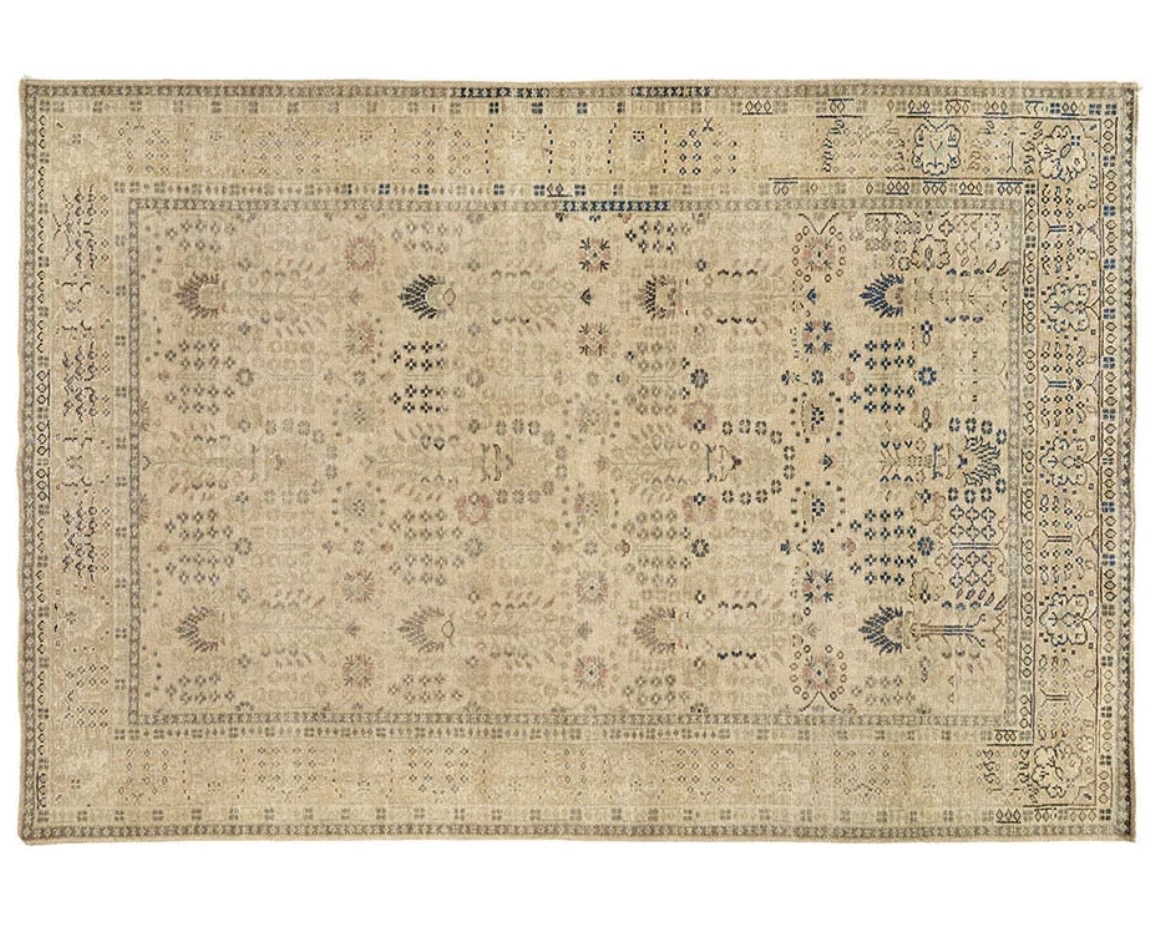 Patterned Persian rug in warm beige under a tan leather sofa