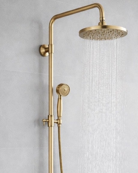 Brushed brass exposed shower system with rain head and handset adds warmth to the neutral bathroom design