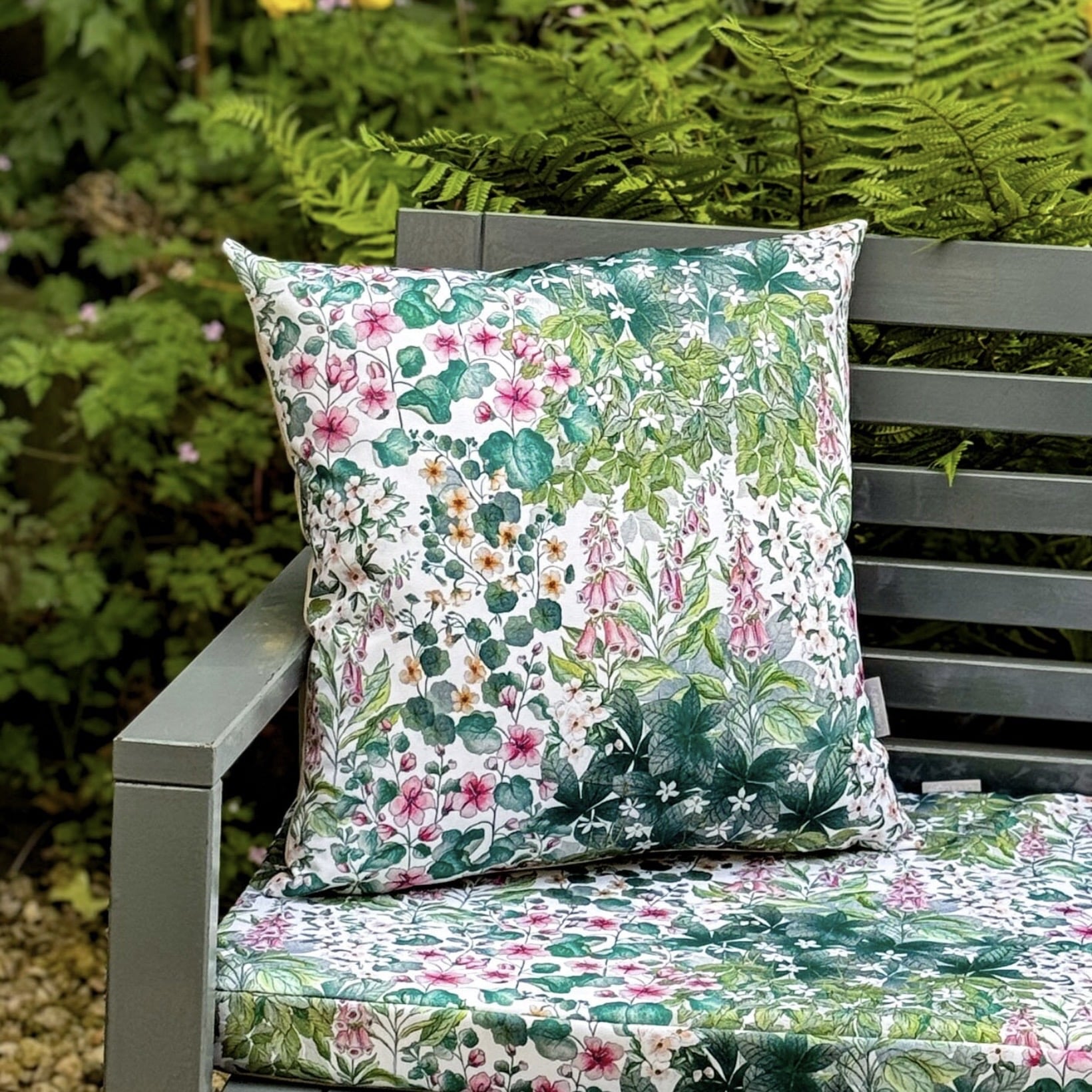 Garden ideas for cosy seating: water-resistant floral outdoor cushion styled on a garden bench with lush green planting