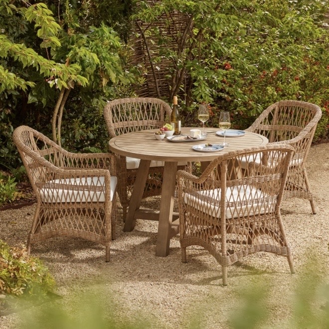 Garden ideas for spring entertaining: rattan four seater round outdoor dining set on a gravel patio in a leafy garden