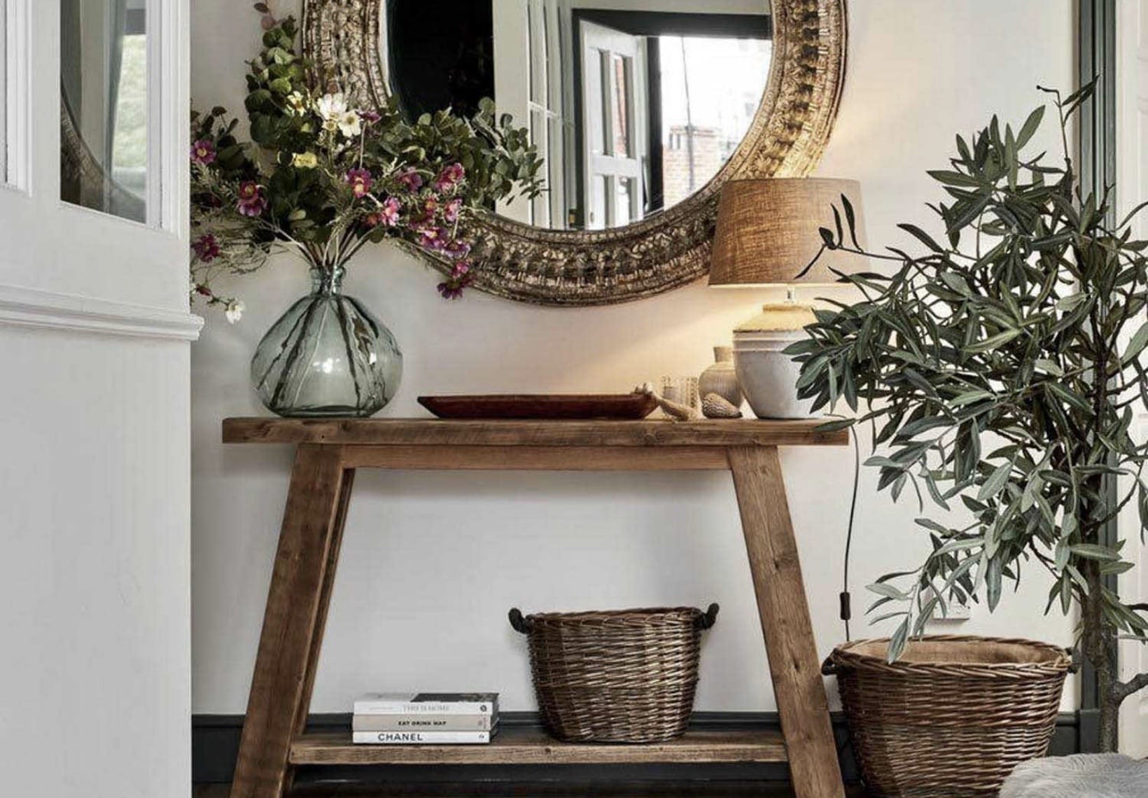 Rustic reclaimed wood hallway console table with storage shelf, styled with a round vintage mirror and greenery