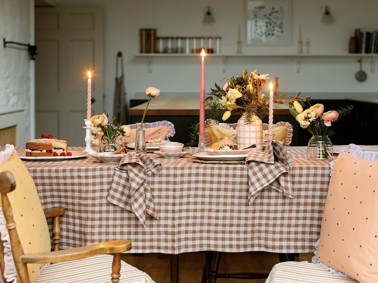 Gingham tablecloth styled with candles and cushions in a relaxed home setting