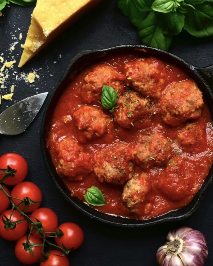 Greek lamb meatballs simmered in rich tomato sauce, served in a shallow bowl with herbs – a cosy weekend supper idea.