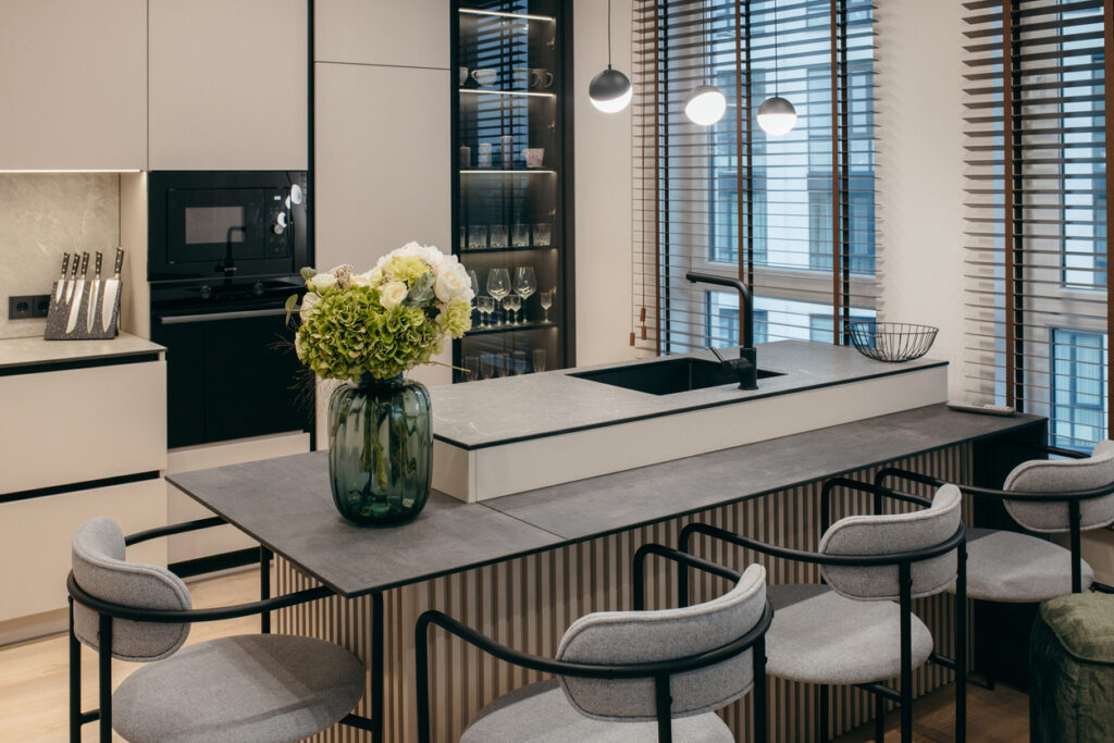 Small dining room ideas: kitchen breakfast bar used as a dining table with upholstered stools and dining pendant lighting in a compact open-plan layout.