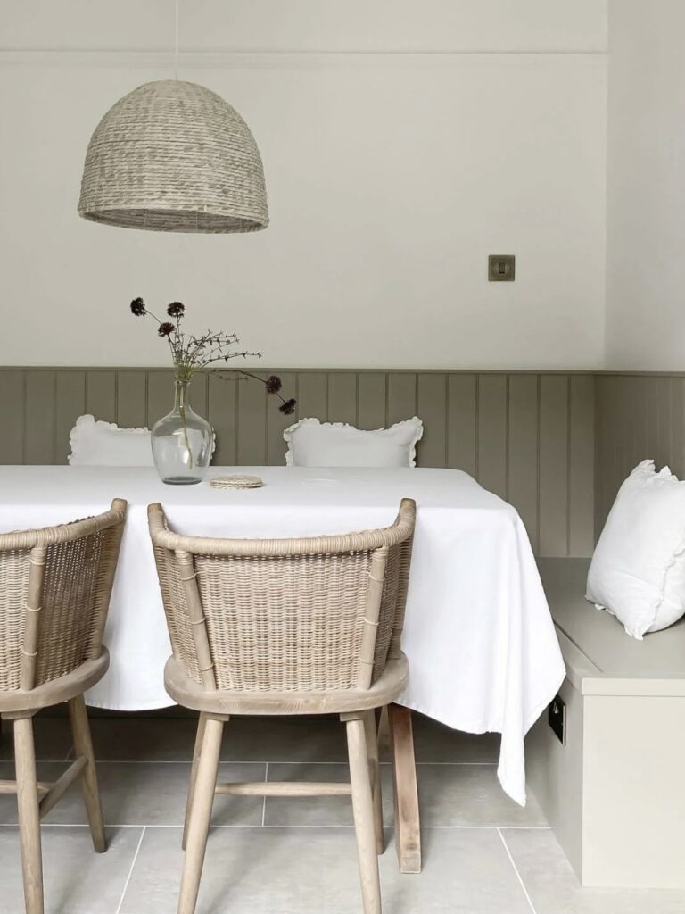 Light grey painted panelling in a small dining room with built-in bench seating and woven pendant light, showing how soft neutral colour makes compact spaces feel larger