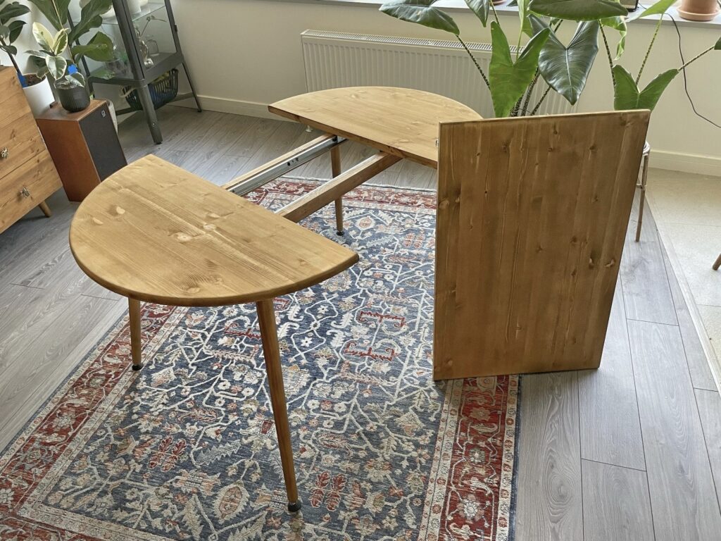Small dining room ideas: extendable round wooden dining table shown mid-extension, expanding for extra seating in a compact room.