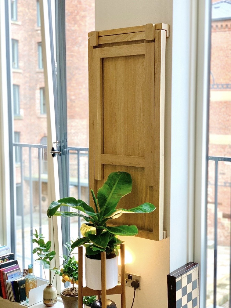 Small dining room ideas showing a solid oak Murphy-style wall table folded vertically to save space in a narrow kitchen-diner.