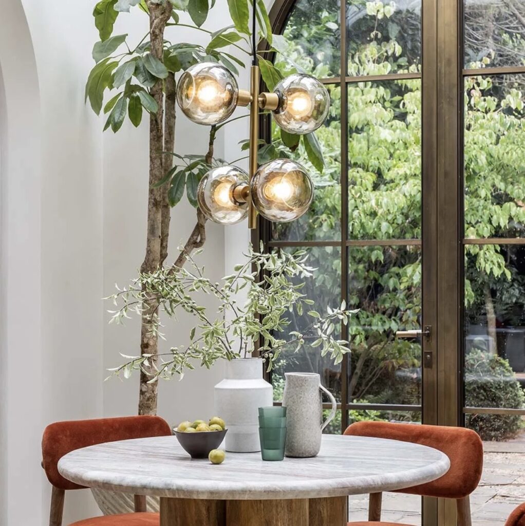 Dining room pendant lighting above a round dining table, creating warm ambient light and depth in a modern dining space.