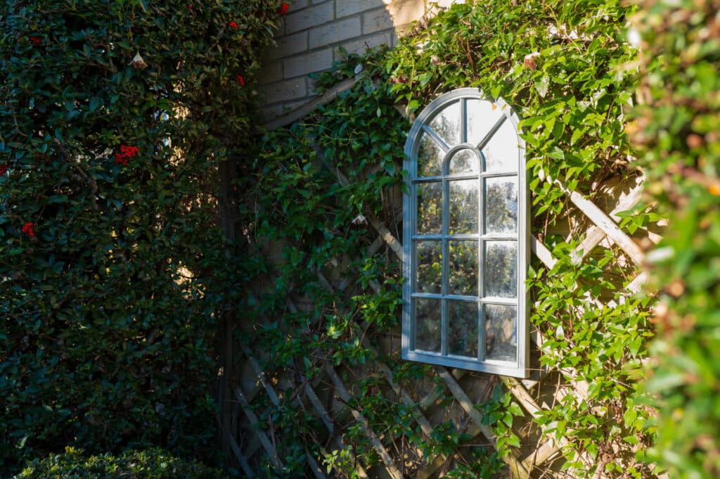 Small garden ideas: arched window garden mirror on trellis to make a small courtyard garden feel bigger