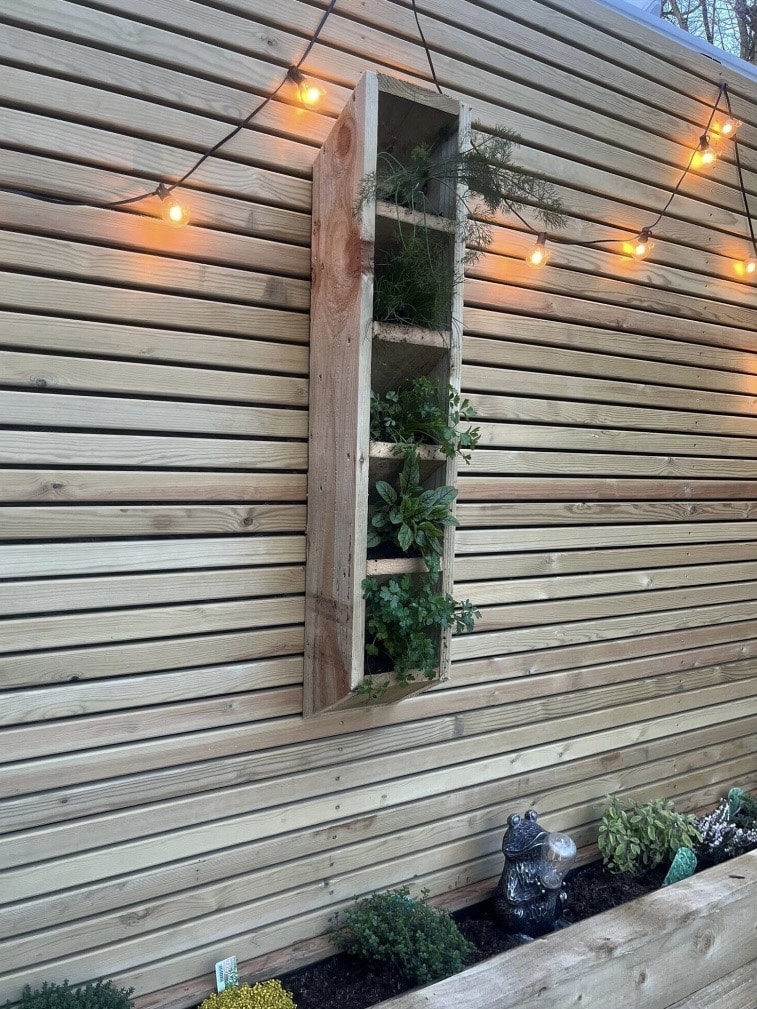 Small garden ideas: slim vertical wall planter for herbs to save space in a small garden