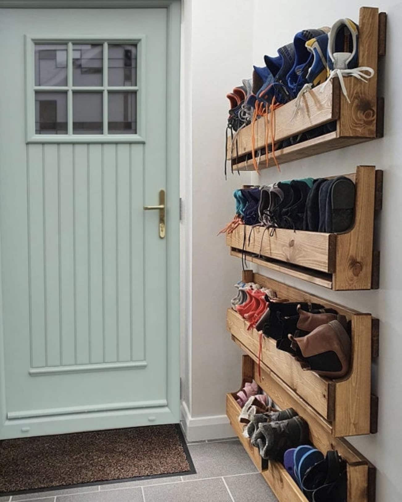 Wall-mounted wooden shoe rack storage in a small hallway by the front door