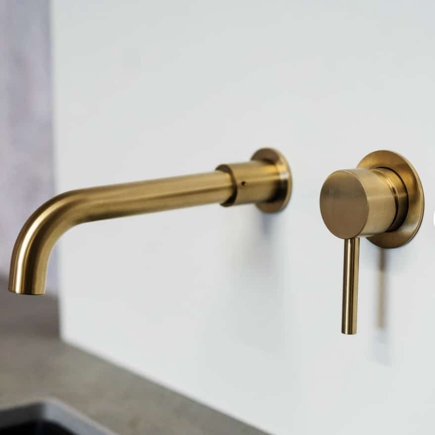 Brass wall mounted basin mixer tap for a coloured bathroom basin