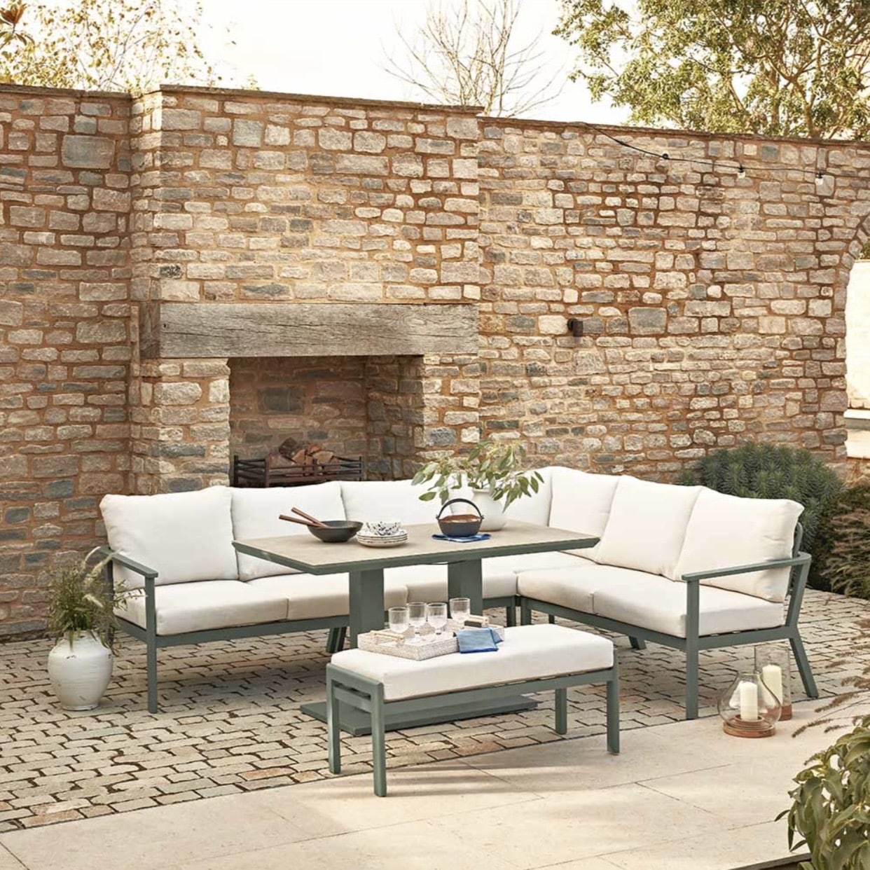 garden Corner sofa with cushions, stool and adjustable table on a paved terrace