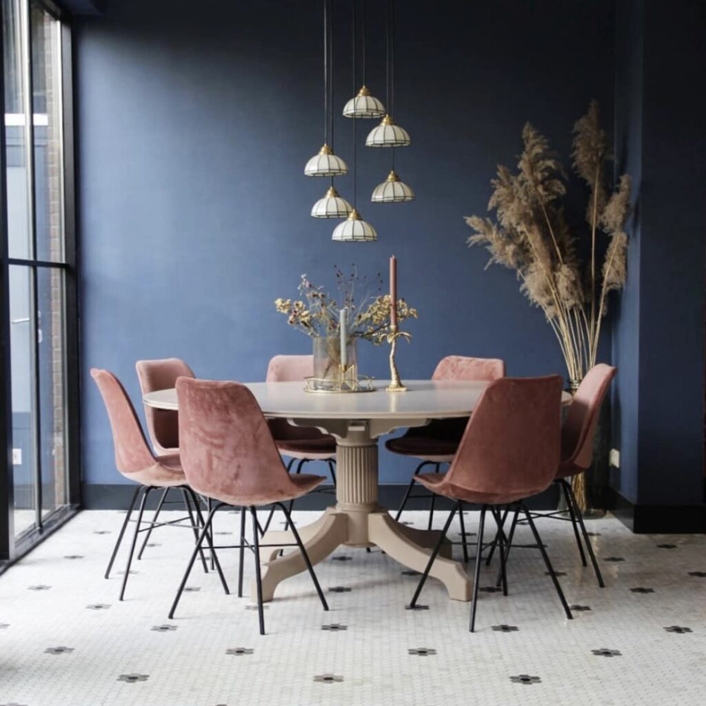 blue dining room colour ideas with deep blue walls round dining table pink velvet chairs and pendant lighting