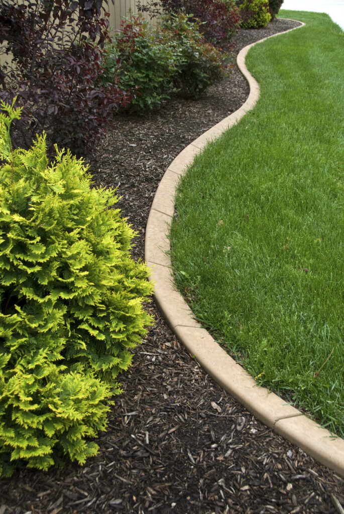 curved concrete garden edging separating lawn from planting bed