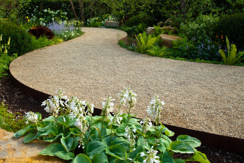 curved metal garden edging separating gravel path from planting border