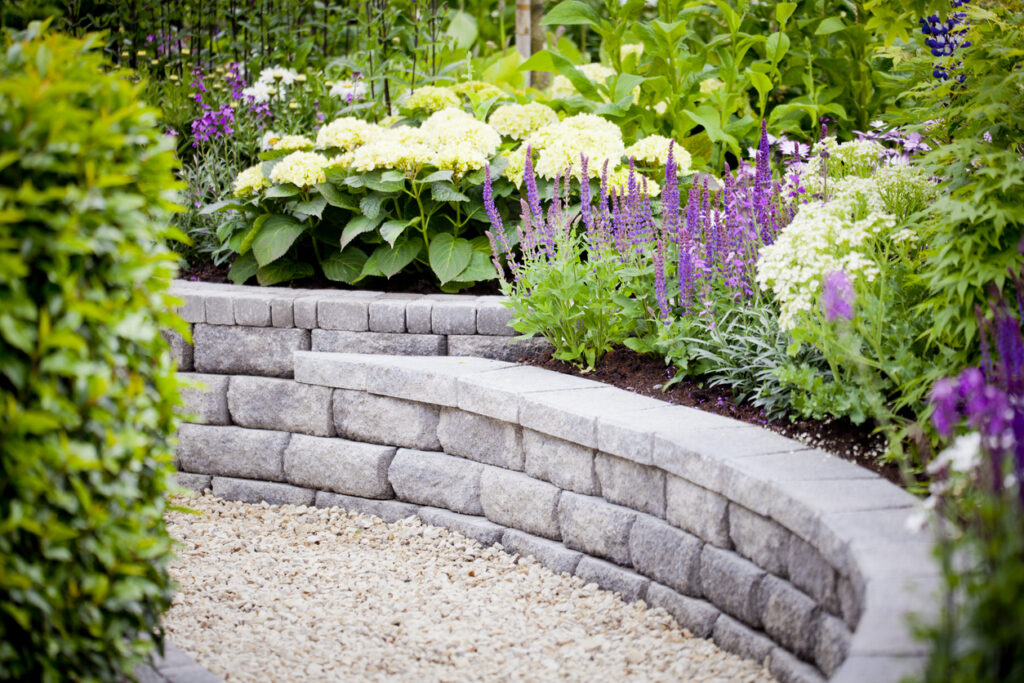 raised garden border edging with curved stone blocks and flower bed planting