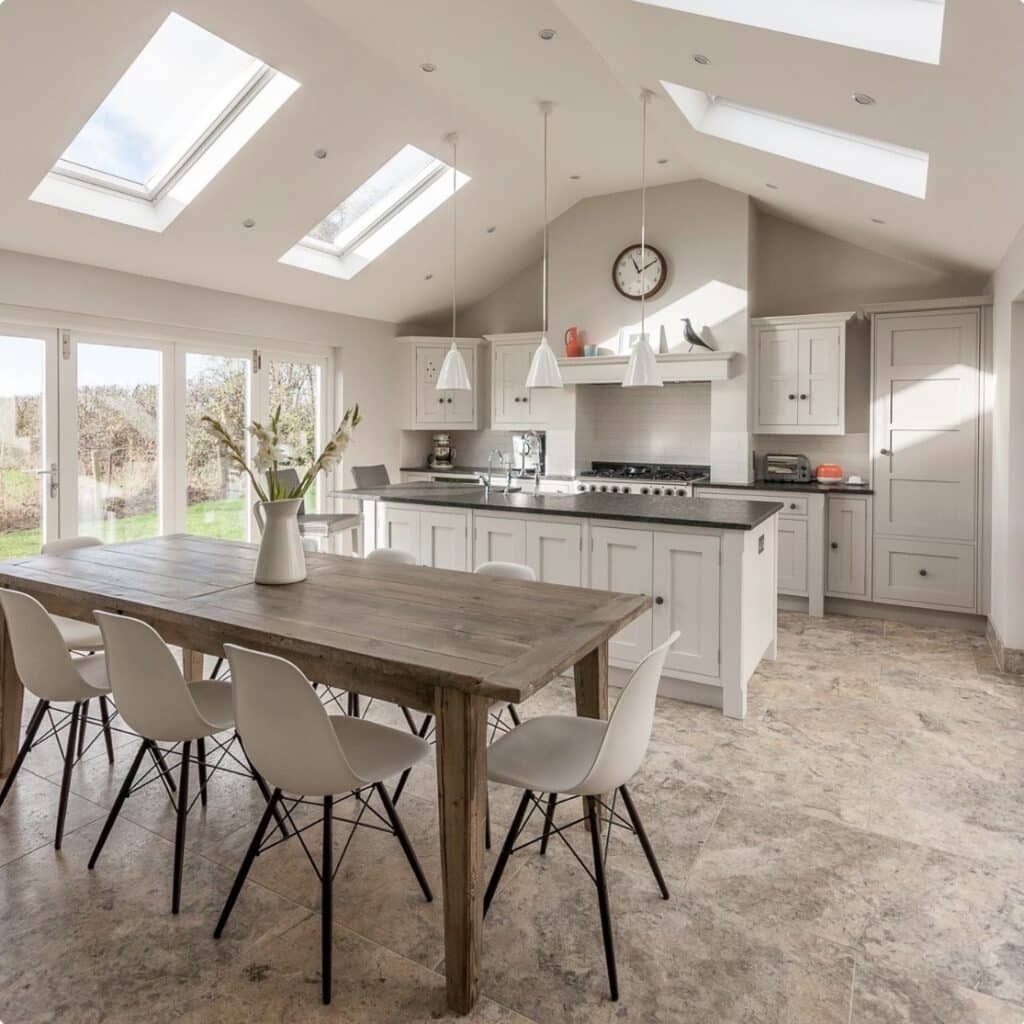 Kitchen dining room ideas with Strong White cabinets, chalky neutral tones, rooflights and a rustic wooden dining table