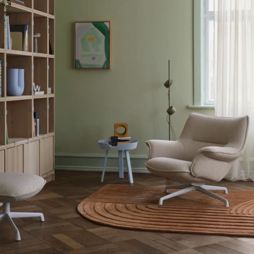 Minimalist orange living room with sculptural burnt orange rug and neutral armchair