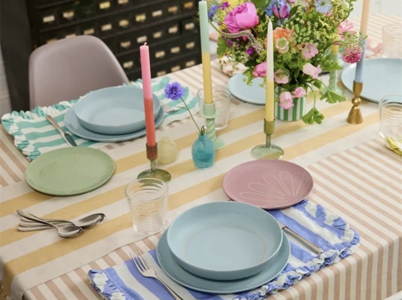 Spring table setting ideas with pastel plates, striped tablecloth and colourful candles
