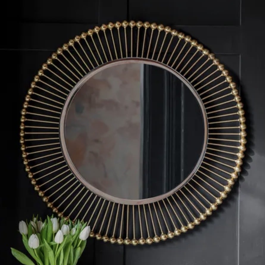 Round gold sunburst mirror in a luxury beige bedroom