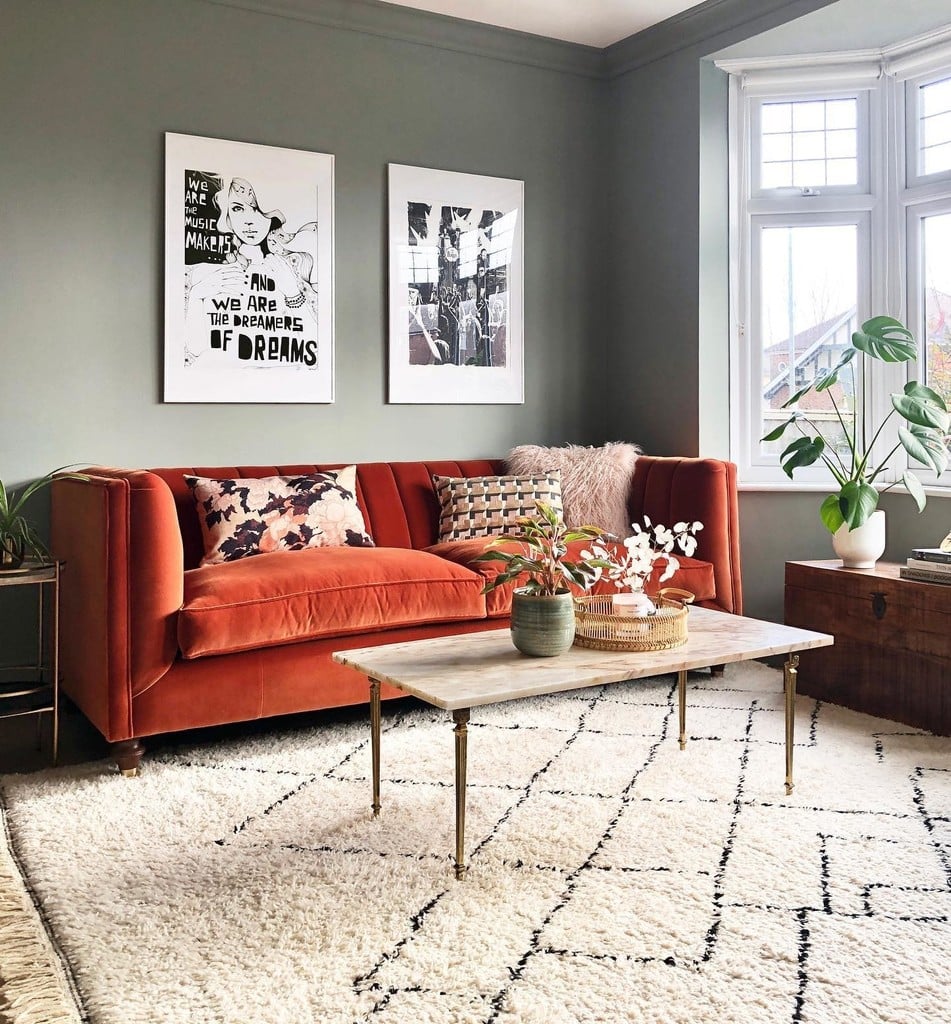 Burnt orange velvet sofa against walls painted in Farrow & Ball Pigeon, with blush pink cushions and a Berber-style rug