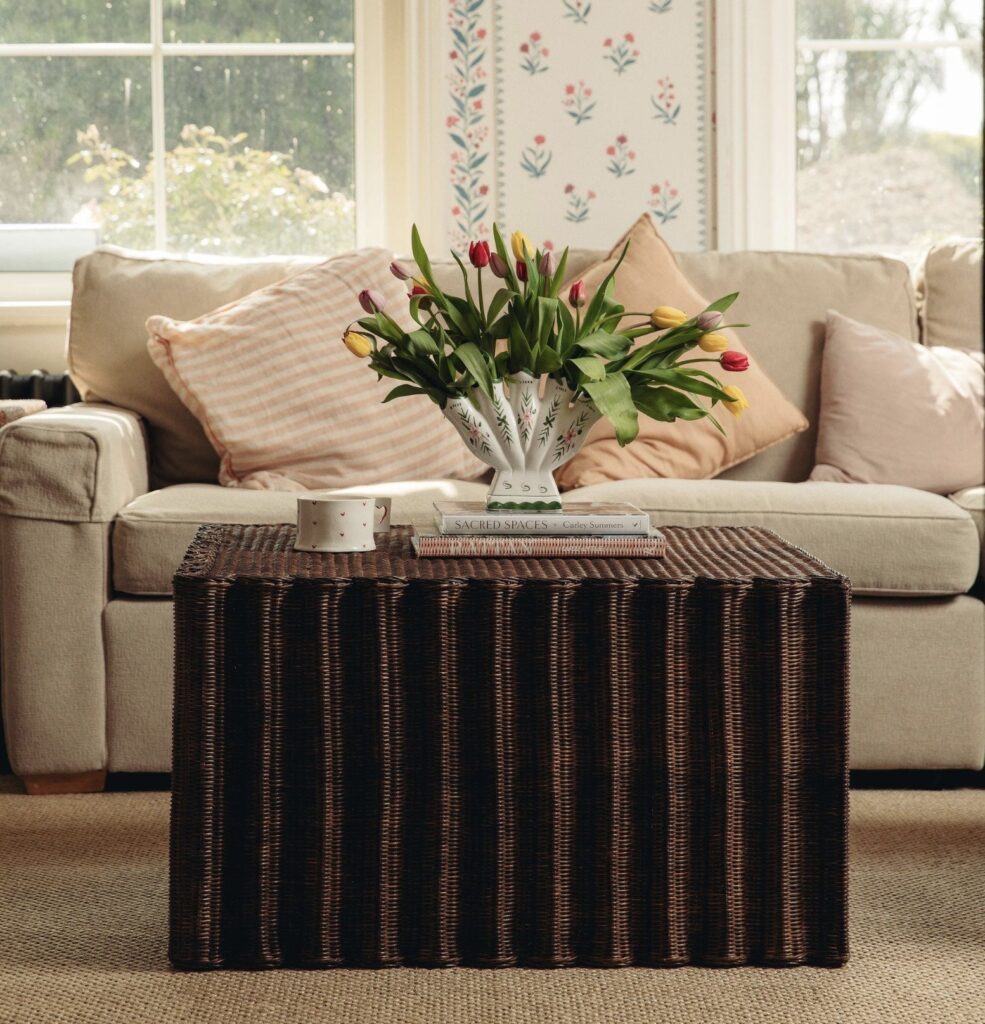 Tulips arranged in a patterned vase on the Daisy Rattan Coffee Table in front of a soft neutral sofa, showing coffee table décor ideas with flowers.