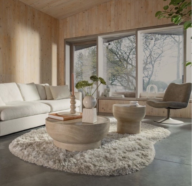 Neutral coffee table decor ideas with a round stone-look coffee table, soft tonal styling, and a cream sofa in a calm modern living room.